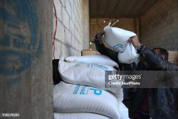 Syrian Arab Red Crescent volunteers and citizens offload aid from a lorry after an aid convoy arrived in the town of Utaya, in the Syrian rebel...