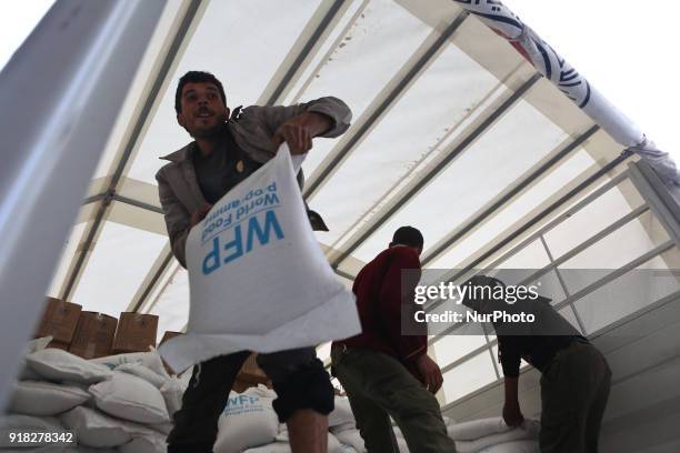 Syrian Arab Red Crescent volunteers and citizens offload aid from a lorry after an aid convoy arrived in the town of Utaya, in the Syrian rebel...