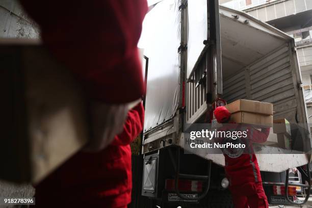 Syrian Arab Red Crescent volunteers offload aid from a lorry after an aid convoy arrived in the town of Douma, in the Syrian rebel enclave of Eastern...