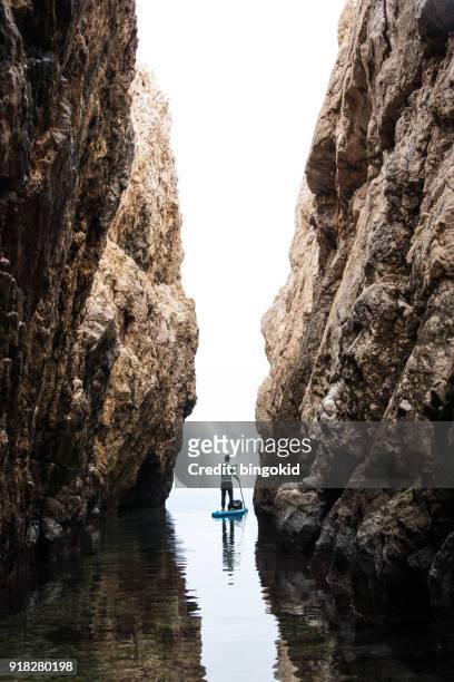 man paddling through narrow cliffs - new adventure stock pictures, royalty-free photos & images