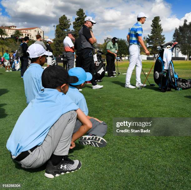 Three young fans watch Jordan Spieth hit tee shots on the driving range during the Pro-Am round for the Genesis Open at Riviera Country Club on...