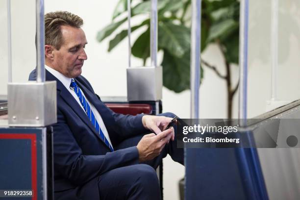 Senator Jeff Flake, a Republican from Arizona, checks a mobile device while sitting on the Senate Subway in the basement of the U.S. Capitol in...