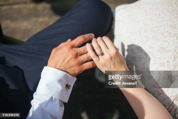 groom holding brides hand with wedding ring on her finger - jovanat stock pictures, royalty-free photos & images