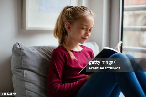 junge teenager-mädchen lesebuch im wohnzimmer - poems stock-fotos und bilder