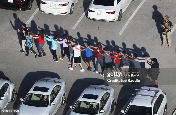 People are brought out of the Marjory Stoneman Douglas High School after a shooting at the school that reportedly killed and injured multiple people...