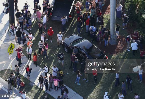 People wait for loved ones as they are brought out of the Marjory Stoneman Douglas High School after a shooting at the school that reportedly killed...