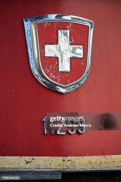 coat of arms of switzerland. a detail of a red swiss train with chrome swiss flag symbol at zurich central station, switzerland - hauptbahnhof zürich stock-fotos und bilder