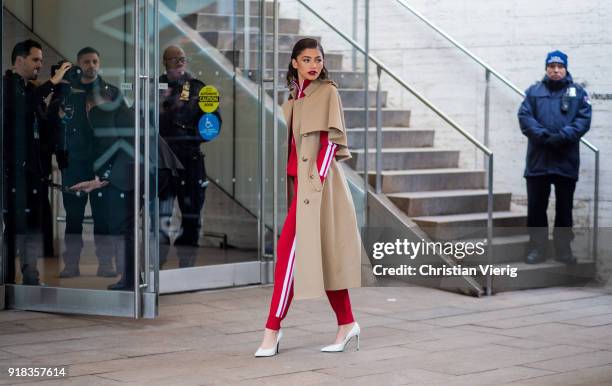 Zendaya wearing trench coat, red track suit, white heels seen outside Michael Kors on February 14, 2018 in New York City.