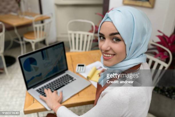 muslim woman doing the books at a restaurant - islamic finance stock pictures, royalty-free photos & images