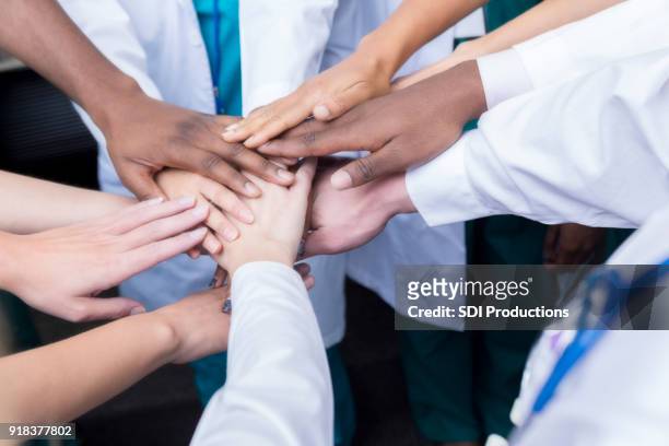 groep van uniforme beroepsbeoefenaren in de gezondheidszorg - handen ineengevouwen stockfoto's en -beelden