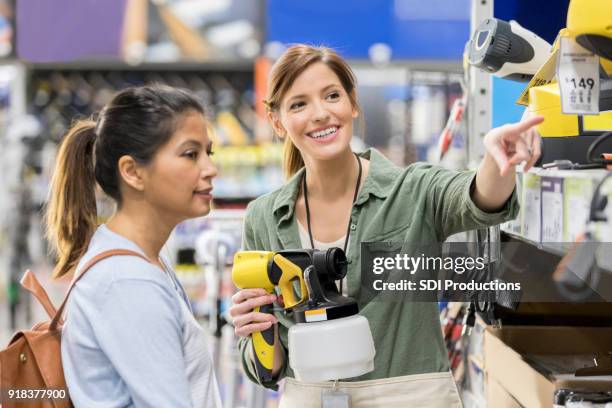 hardware store salesperson shows paint sprayers to customer - loja de ferragens imagens e fotografias de stock