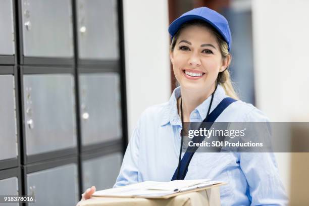 smiling female mail carrier at work - postal worker stock pictures, royalty-free photos & images