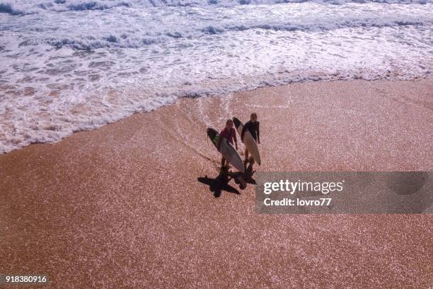 aerial view of friends walking down the coastline with surfboards - city to surf stock pictures, royalty-free photos & images