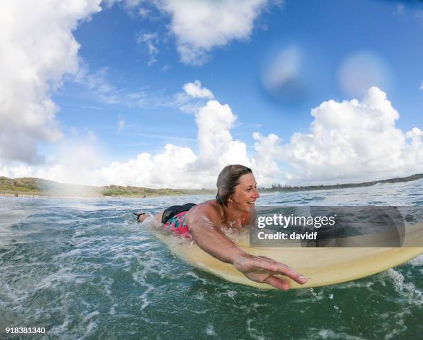 applying frau surfen am strand - byron bay stock-fotos und bilder