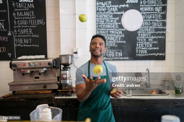black salesman working at a cafe juggling with fruits behind the counter having fun - juggling stock pictures, royalty-free photos & images