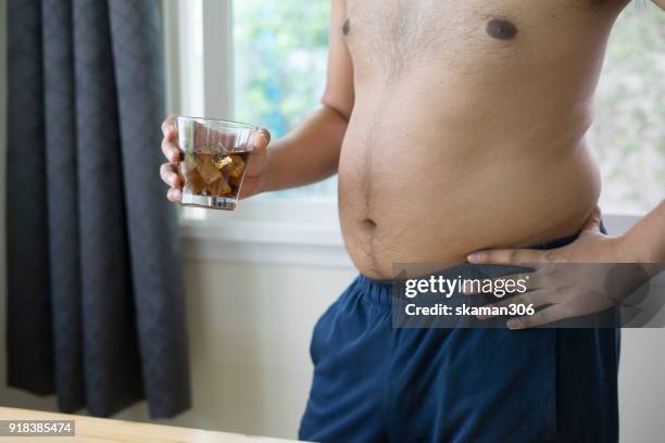 overweight man holding glass of aerated soft drink - aerated drinks stockfoto's en -beelden
