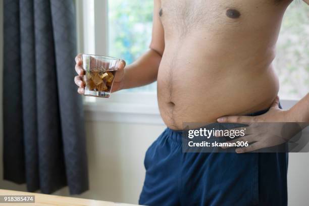 overweight man holding glass of aerated soft drink - fat asian man stockfoto's en -beelden