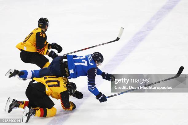 Christian Ehrhoff and Felix Schutz of Germany crash into Mika Pyorala of Finland during the Men's Ice Hockey Preliminary Round Group C game on day...