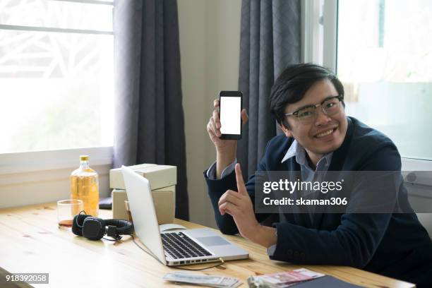 asian business man holding smartphone and tablet for online shopping with laptop computer and with packaged to be shipped global - quitar fondo de imagen online fotografías e imágenes de stock