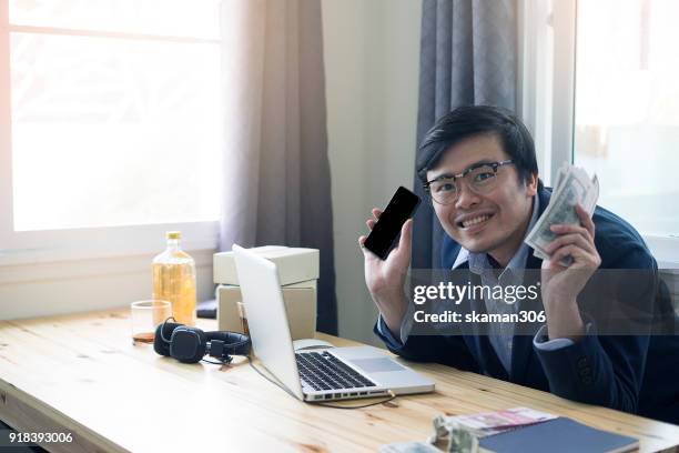 asian business man holding smartphone and tablet for online shopping with laptop computer and with packaged to be shipped global - quitar fondo de imagen online fotografías e imágenes de stock