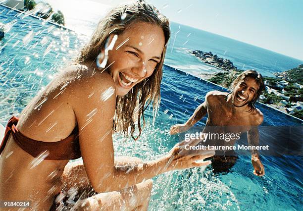 couple splashing in swimming pool - man splashed with colour fotografías e imágenes de stock