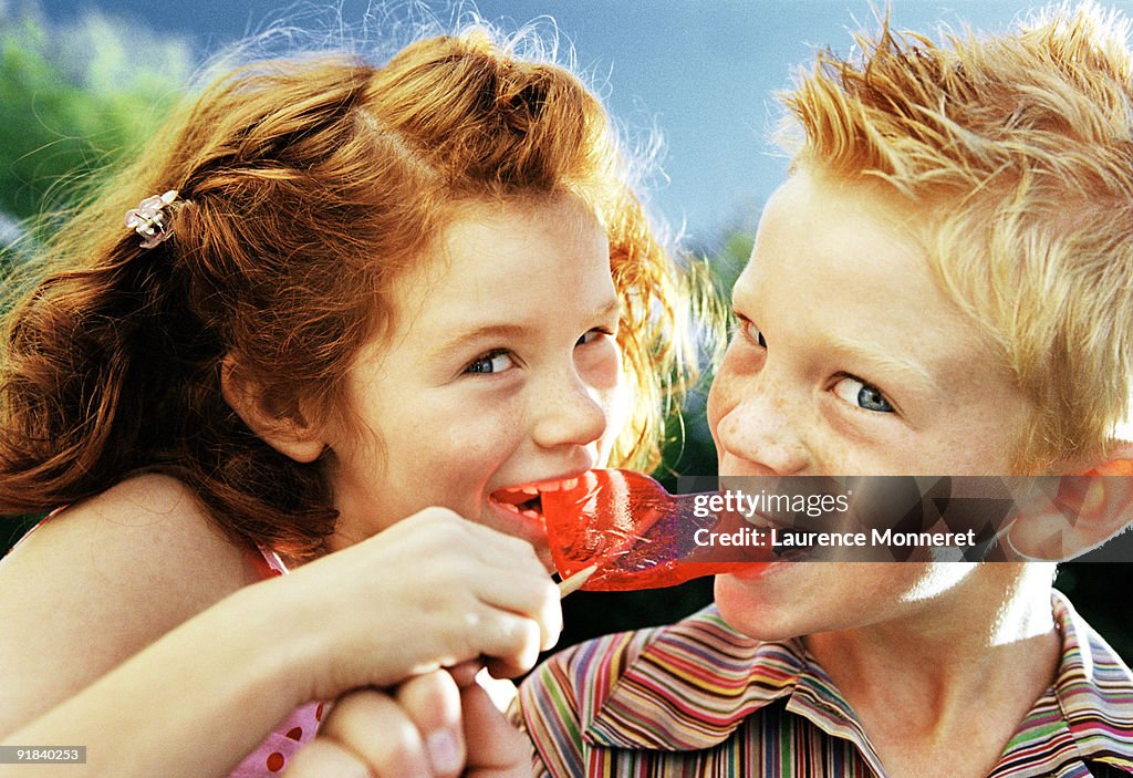 Boy and girl eating lollipop