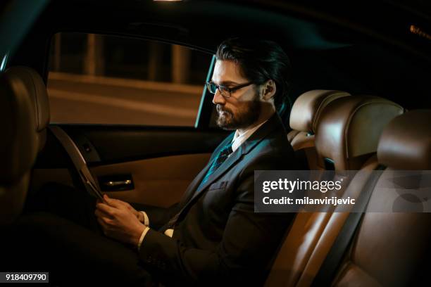 businessman in car at back seat - chauffeur stock pictures, royalty-free photos & images