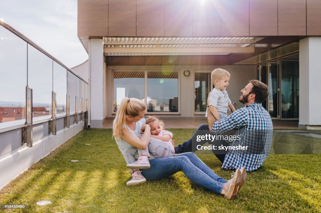 Happy family playing on the grass in front of their penthouse.