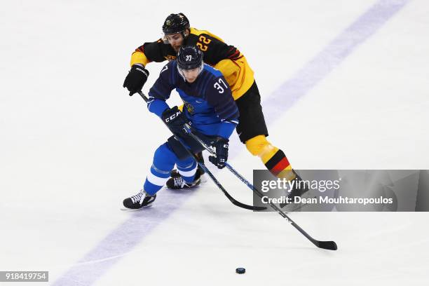 Matthias Plachta of Germany battles for the puck with Karri Ramo of Finland during the Men's Ice Hockey Preliminary Round Group C game on day six of...