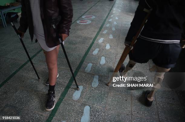 In this photograph taken on February 13, 2018 shows Afghan amputees practice walking with their prosthetic legs at a hospital run by the...