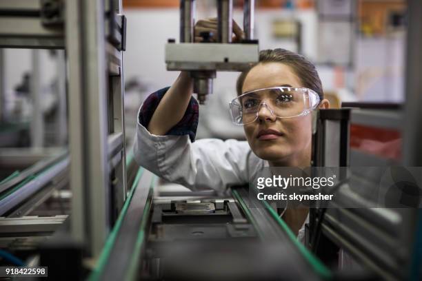 female engineer examining machine part on a production line. - groundbreaking female scientists stock pictures, royalty-free photos & images