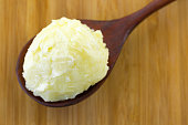 Cold pressed unrefined Shea butter fat extracted from nut seed of African Shea tree in wooden spoon