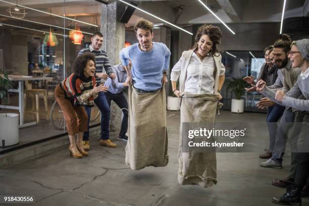 carefree freelancers having fun during a sack race at casual office. - sack race stock pictures, royalty-free photos & images