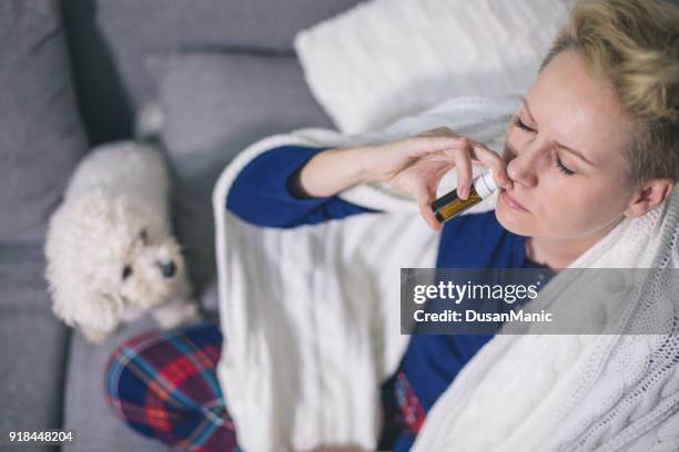 sick young woman taking nose drops at home - covering nose stock pictures, royalty-free photos & images