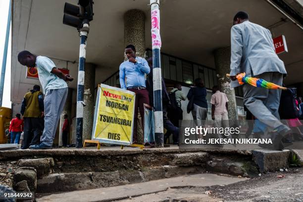 Man stands with a newspaper board with the headline reading 'Morgan Tsvangirai dies' as members of Zimbabwe's opposition party 'Movement for...