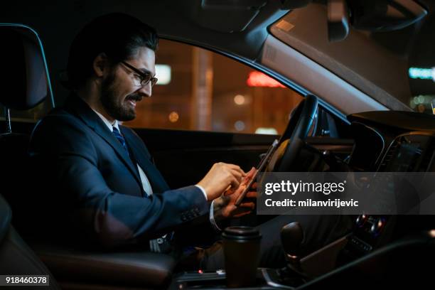 young businessman using smartphone while driving - chauffeur stock pictures, royalty-free photos & images