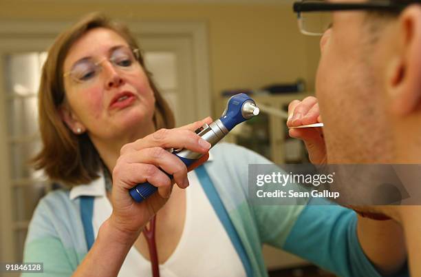 Family doctor checks a patient's mouth and throat at her office on October 13, 2009 in Berlin, Germany. German political parties currently involved...