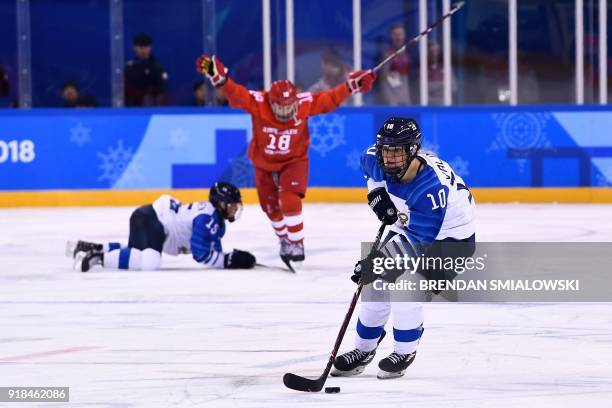 Finland's Linda Valimaki controls the puck in front of teammate Minnamari Tuominen and Russia's Olga Sosina in the women's preliminary round ice...