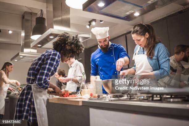 giovane chef che assiste un corso di cucina e spiega alcuni consigli e trucchi - cooking event foto e immagini stock