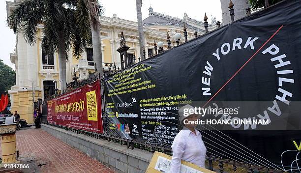 Street vendor walks past a poster hung outside the Hanoi Opera house advertising a performance of the New York Philharmonic in Hanoi on October 13,...