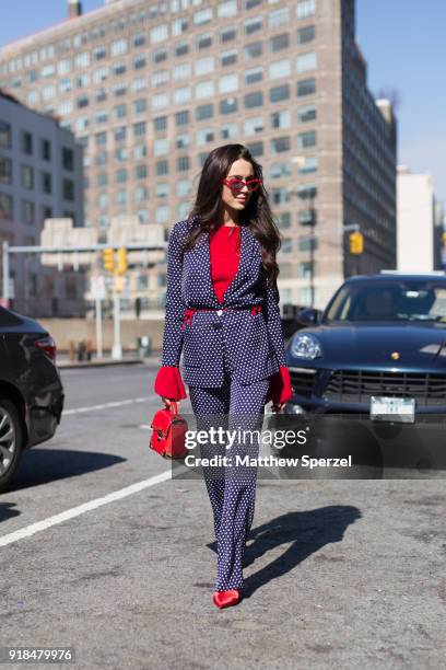 Guest is seen on the street attending Leanne Marshall during New York Fashion Week wearing a navy polkadot suit with red sweater on February 14, 2018...