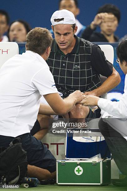 Andy Rodick of the United States receives treatment from ATP trainer Michael Novotny before retiring from his match against Stanilas Wawrinka of...