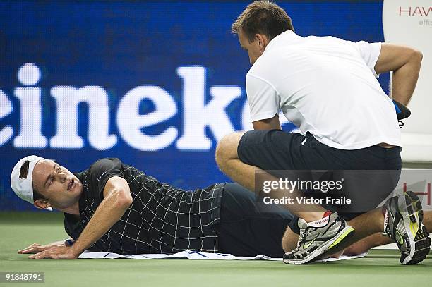 Andy Rodick of the United States receives treatment from ATP trainer Michael Novotny before retiring from his match against Stanilas Wawrinka of...