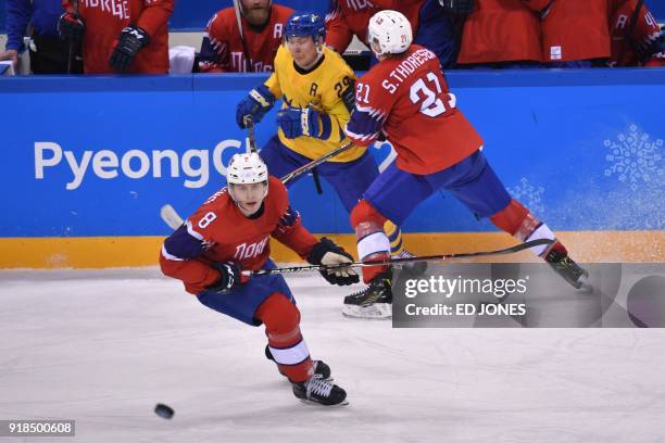 Norway's Steffen Thoresen tackles Sweden's Erik Gustafsson in front of Norway's Mathias Trettenes in the men's preliminary round ice hockey match...