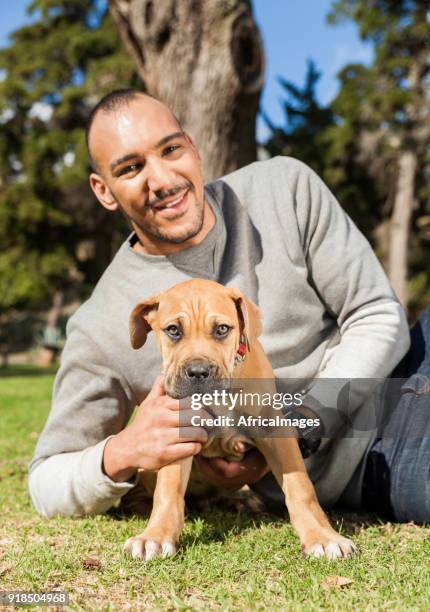 young man and his puppy on the grass at the park. - boerboel stock pictures, royalty-free photos & images