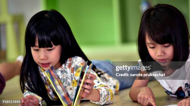 kindergarten girls  in read magazines in an international school library.teacher ,education, kid and primary school concept . - portrait of school children and female teacher in field stock pictures, royalty-free photos & images