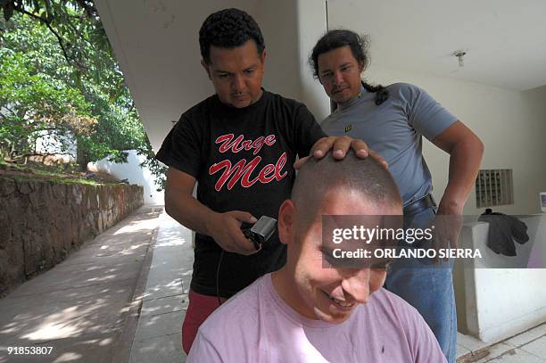 Supporter of deposed Honduran President Manuel Zelaya cuts the hair of Brazilian newspaper Folha de Sao Paulo's journalist Fabiano Maisonnave at the...