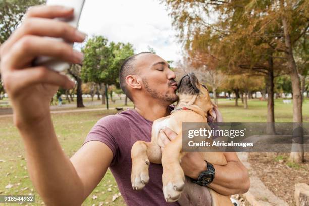 jonge man nemen van een selfie van hem zoenen zijn pup. - boerboel stockfoto's en -beelden