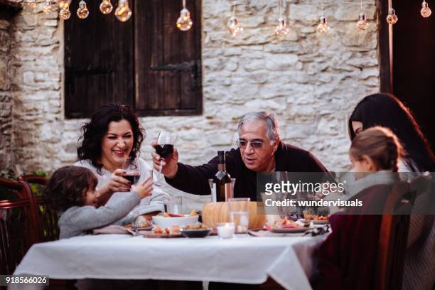 familie spaß und toasten mit getränken am esstisch - festmahl stock-fotos und bilder
