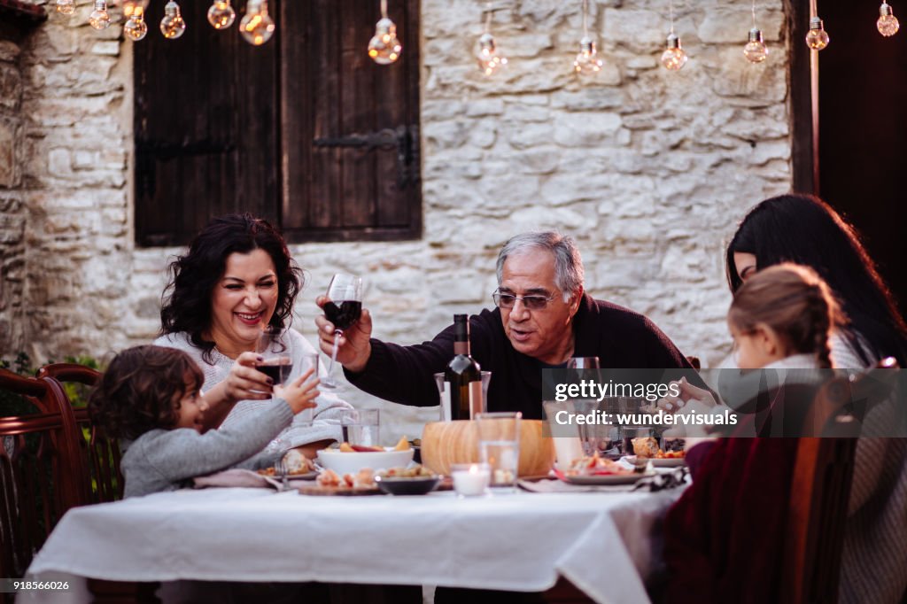 Family having fun and toasting with drinks at dining table